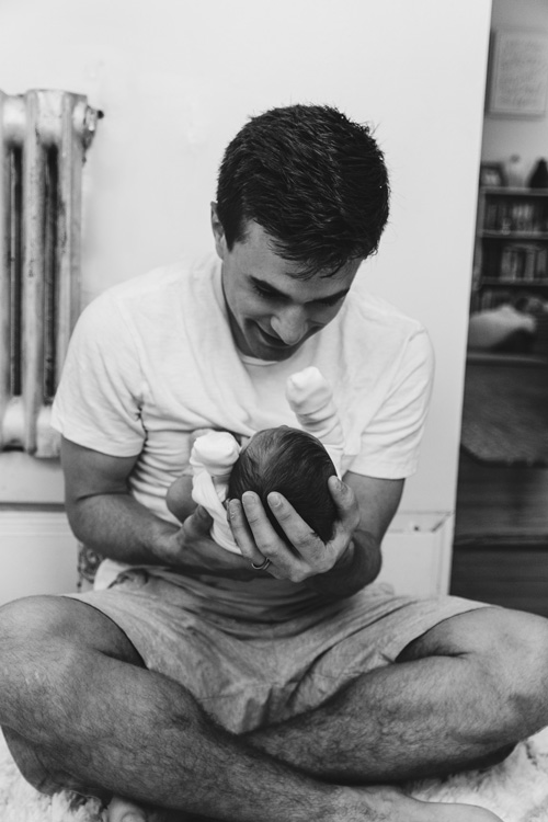 Far som smiler mot nyfødt i armene